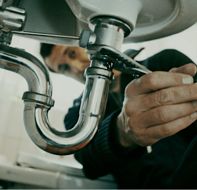 A plumber is fixing a sink pipe.