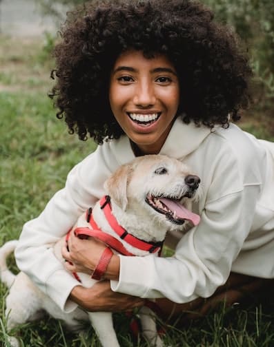 woman smiling and hugging her cute dog in a park