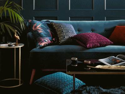 A living room with a blue couch and a plant.