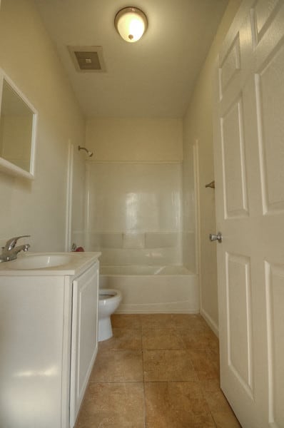 bathroom with white cabinet, white walls and being floor tile