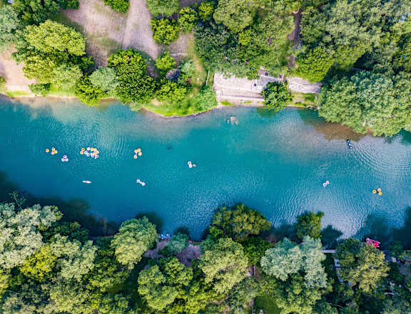 A serene lake surrounded by lush green trees with people enjoying water activities.