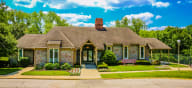 a small brick house with a bench in front of it at Canyon Creek Apartments, Kansas City, 64132