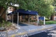 the front of a building with a blue awning and a sign in front