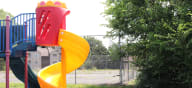 a playground with a yellow and red slide at Canyon Creek Apartments, Missouri