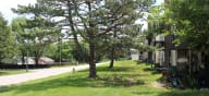 a grassy area with trees in front of a building at Canyon Creek Apartments, Missouri