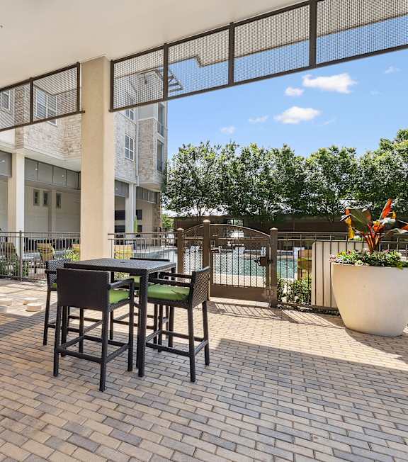 A patio with a table and chairs is surrounded by a glass wall.