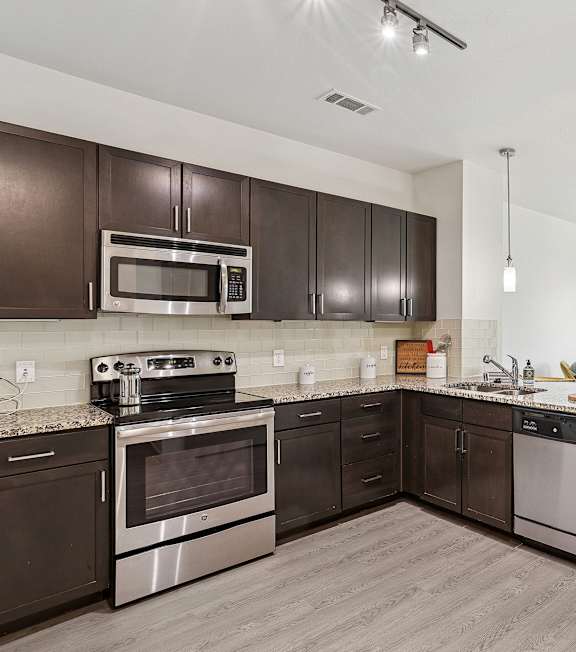 A modern kitchen with dark brown cabinets and stainless steel appliances.