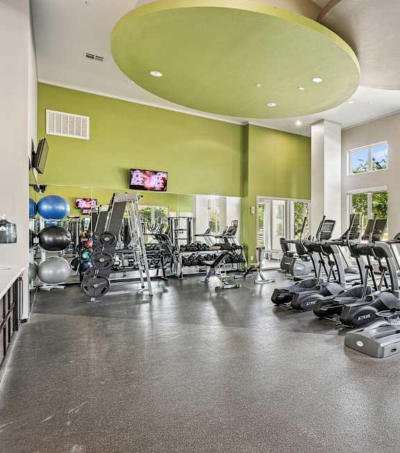 A gym with a variety of equipment including treadmills, weights, and exercise machines.