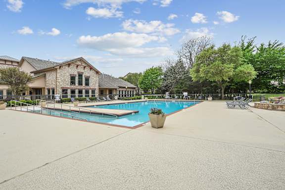 A large outdoor swimming pool surrounded by trees and a building.