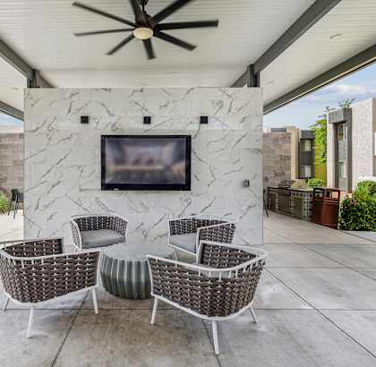 a patio with a stone wall with a tv and chairs