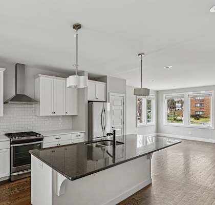 A modern kitchen with white cabinets and a black countertop.