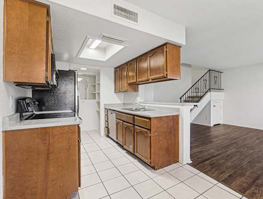 A kitchen with wooden cabinets and a black refrigerator.