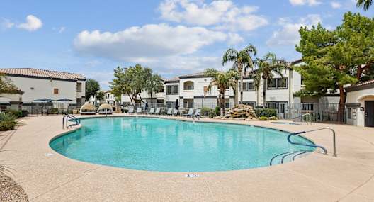A swimming pool surrounded by palm trees and buildings.