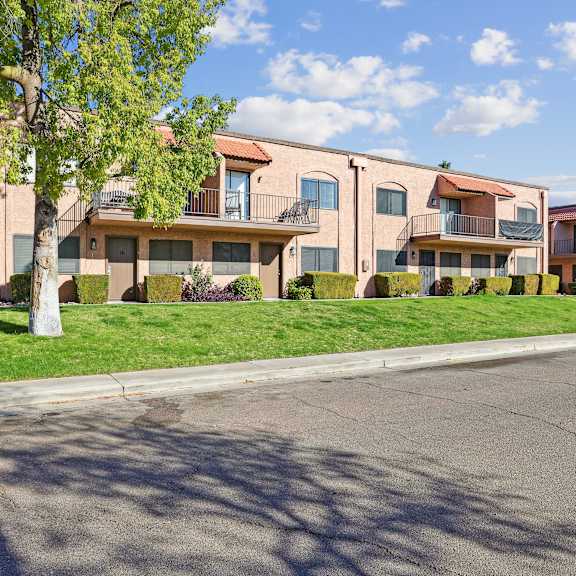 A building with a balcony and a green lawn in front.