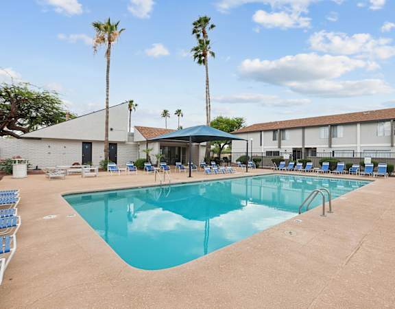 A large swimming pool with a blue cover and a building in the background.