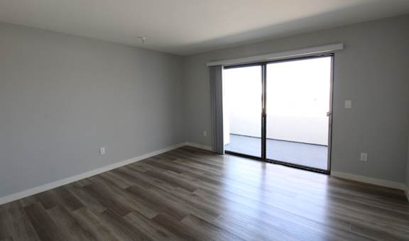 an empty living room with wood floors and a sliding glass door