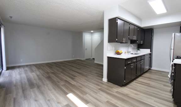 A kitchen with black cabinets and a wooden floor.