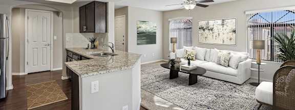 A modern kitchen with a white island and a white sofa in the living room.