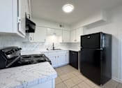 Thumbnail 1 of 15 - a kitchen with a stove and a refrigerator and white cabinets