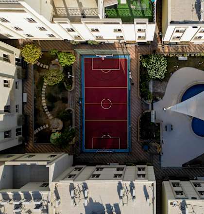 A red soccer field is surrounded by white buildings.