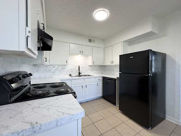 a kitchen with a stove and a refrigerator and white cabinets