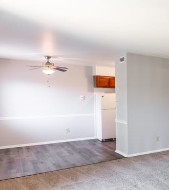 an empty living room with carpet and a door to a bedroom