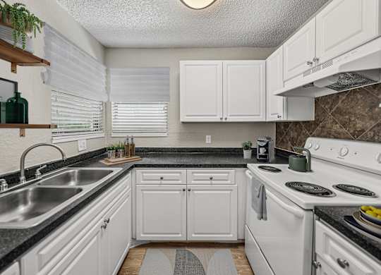 A kitchen with white cabinets and a black countertop.