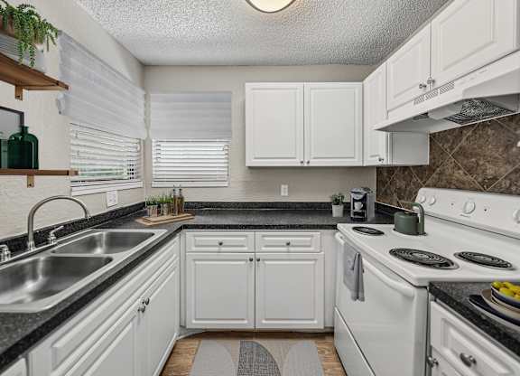 A kitchen with white cabinets and a black countertop.
