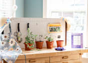 Thumbnail 16 of 17 - A wooden desk with a pegboard and potted plants on it.