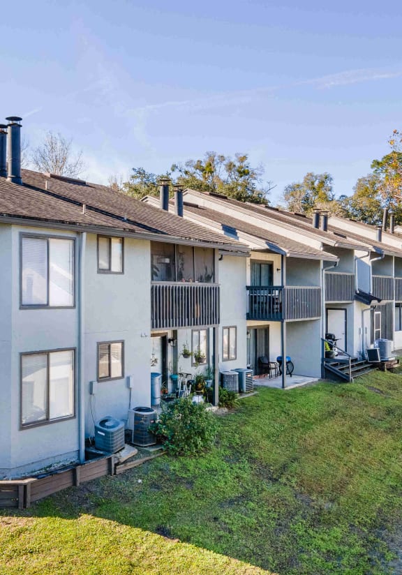 a row of apartments with balconies and a grass yard