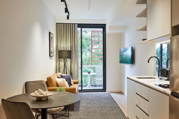 a kitchen and living room with a door to a balcony