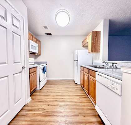 A kitchen with white cabinets and a wooden floor.