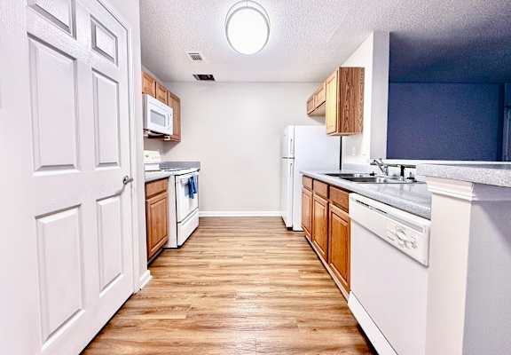 A kitchen with white cabinets and a wooden floor.