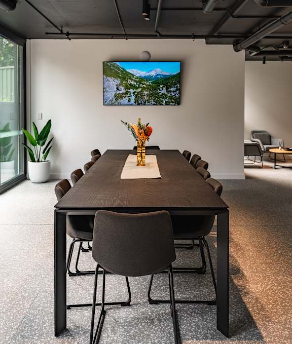 a conference room with a table and chairs and a tv on the wall