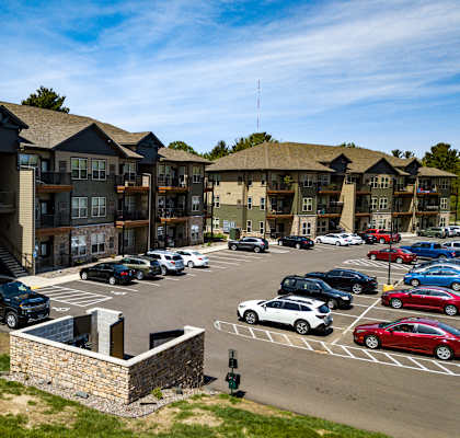 A parking lot with cars and apartment buildings in the background.