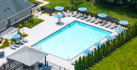 A large outdoor swimming pool surrounded by lawn chairs and umbrellas.