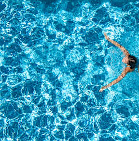 Two people are floating on inflatable rings in a swimming pool.