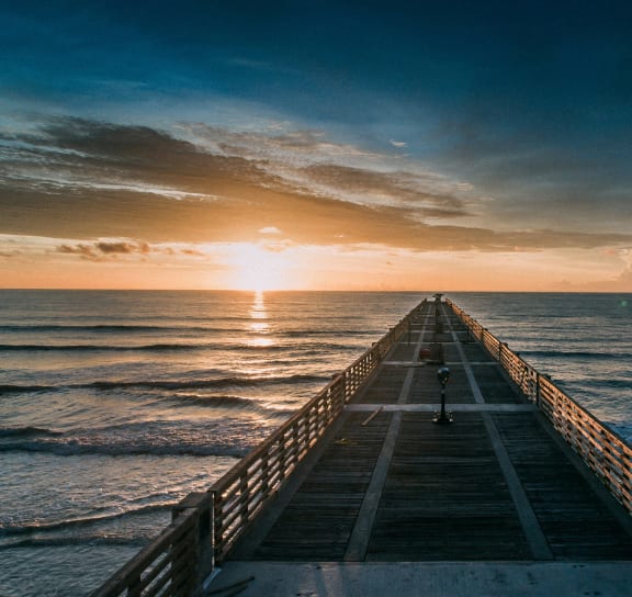 a pier in the ocean at sunset