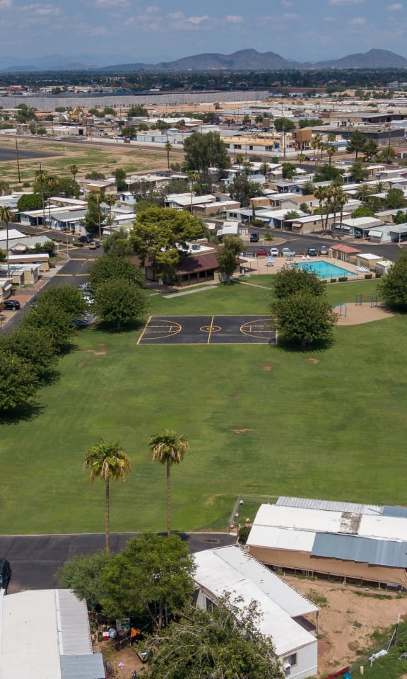 Bird's eye view of Belaire Manor, showing the large grass field, basketball court, playground equipment, and pool.