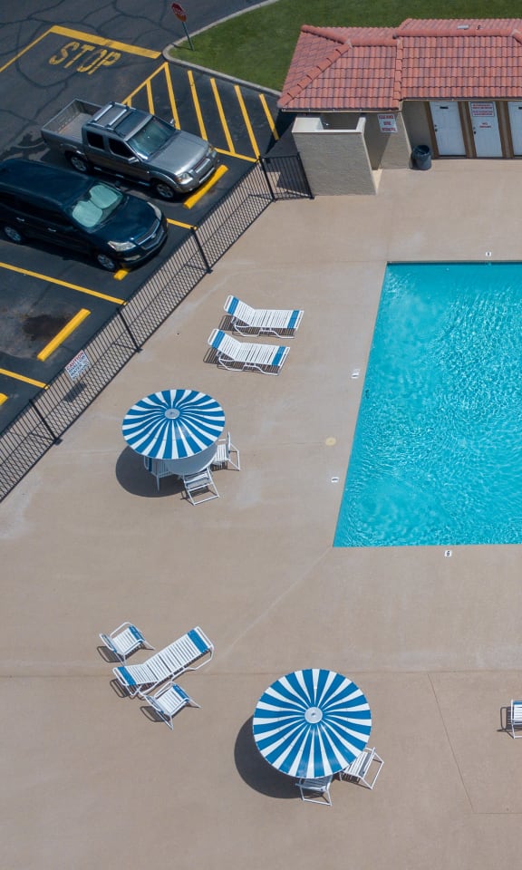 Large swimming pool with lounge chairs, tables and umbrellas
