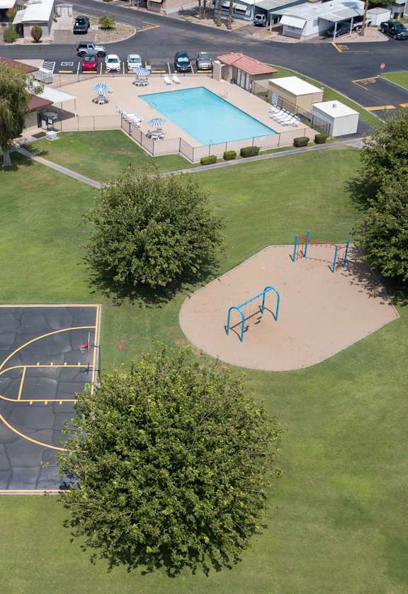 Bird's eye view of Belaire Manor, basketball court, grass area, trees, playground equipment and swimming pool