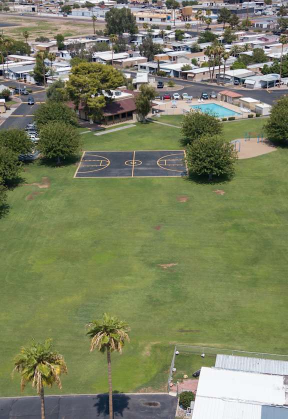 Birds eye view of large grass area, basketball court, pool and mobile homes