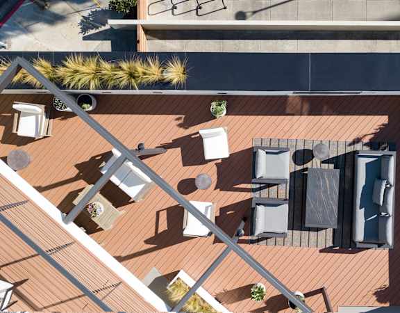 A top-down view of a rooftop patio with furniture and plants.