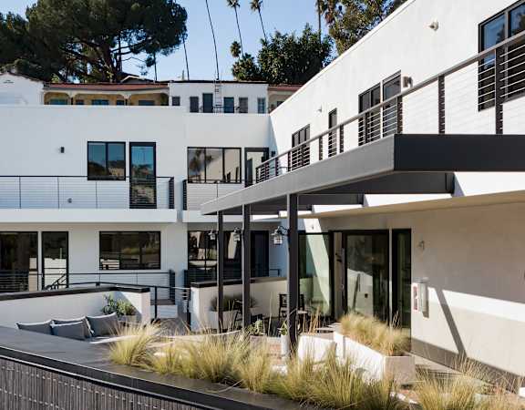 A modern white house with a balcony and a black railing.