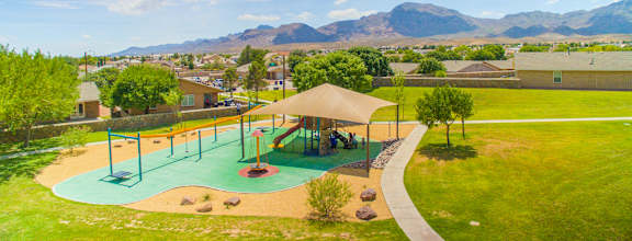an aerial view of a playground with houses and mountains in the background