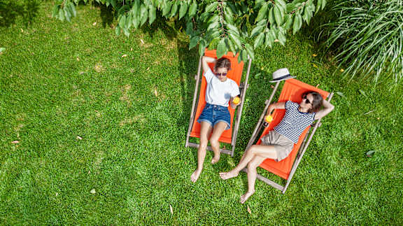 Two people relaxing on chairs in a grassy area.