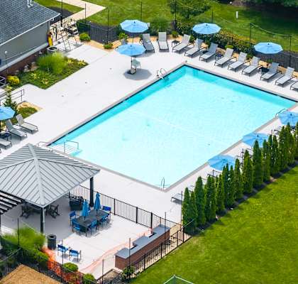 A large outdoor swimming pool surrounded by lawn chairs and umbrellas.