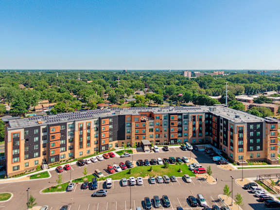 A large apartment complex with a parking lot in front. at Sonder Point 50+ Apartments, Minnesota, 55430