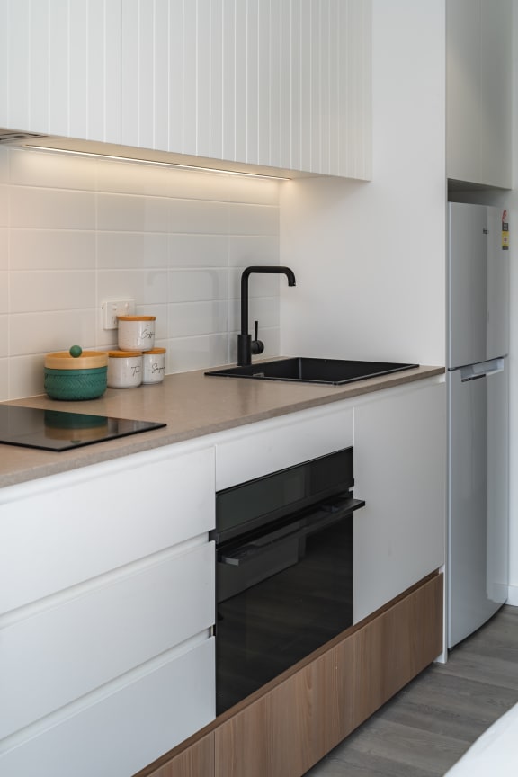 a kitchen with white cabinets and a black oven and sink