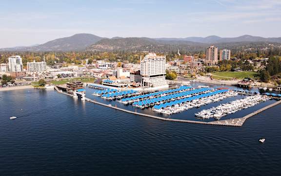 A cityscape with a large body of water in the foreground and a mountain in the background.